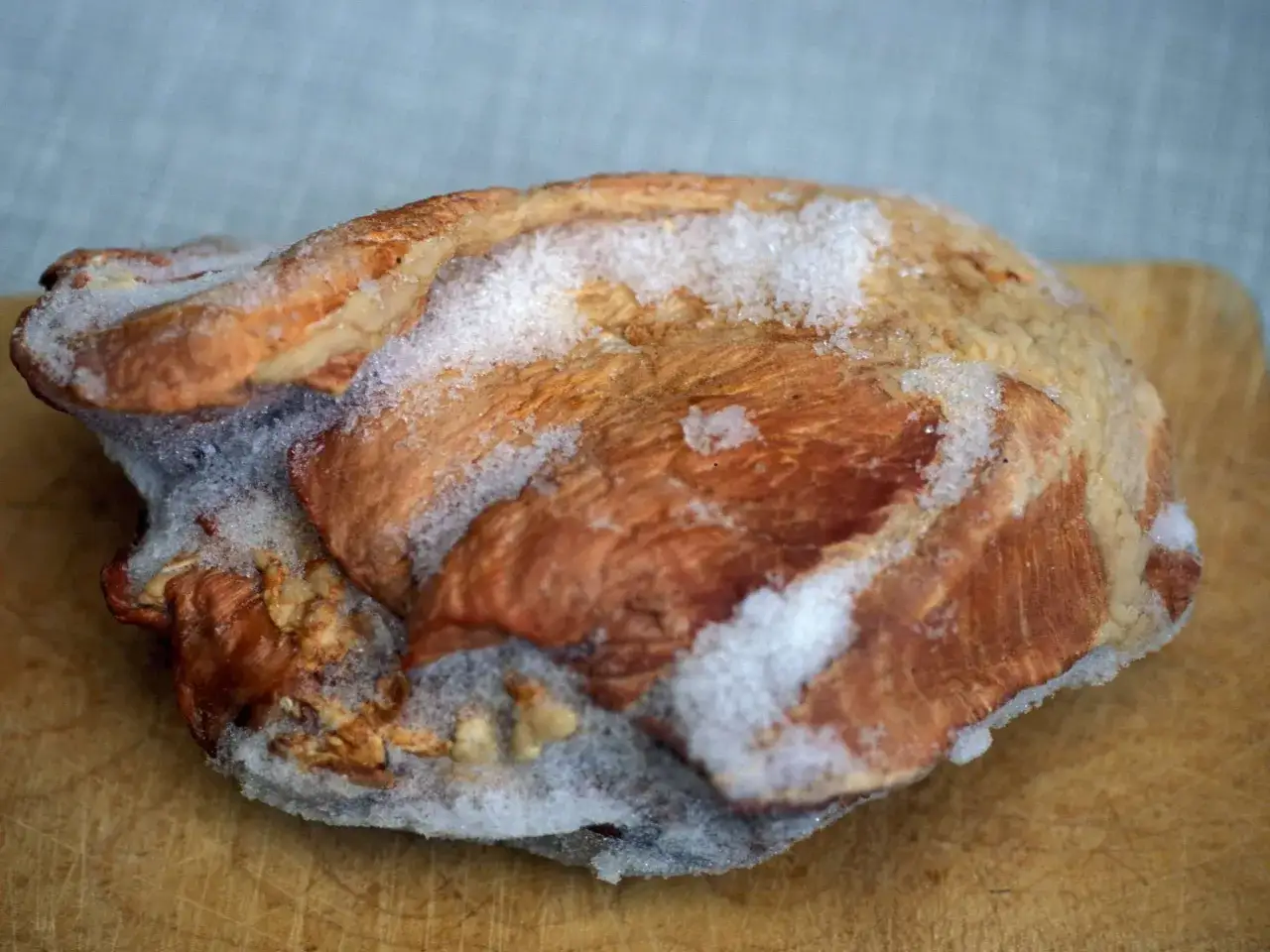 Gefrierbrand essen: Ein St&uuml;ck Fleisch mit Eiskristallen, das auf einem Holzbrett liegt.