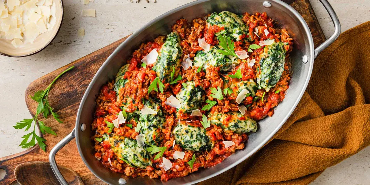 Herzhafte Spinat Ricotta Gnocchi in einer fleischigen Tomatensauce, garniert mit Parmesan und Petersilie.