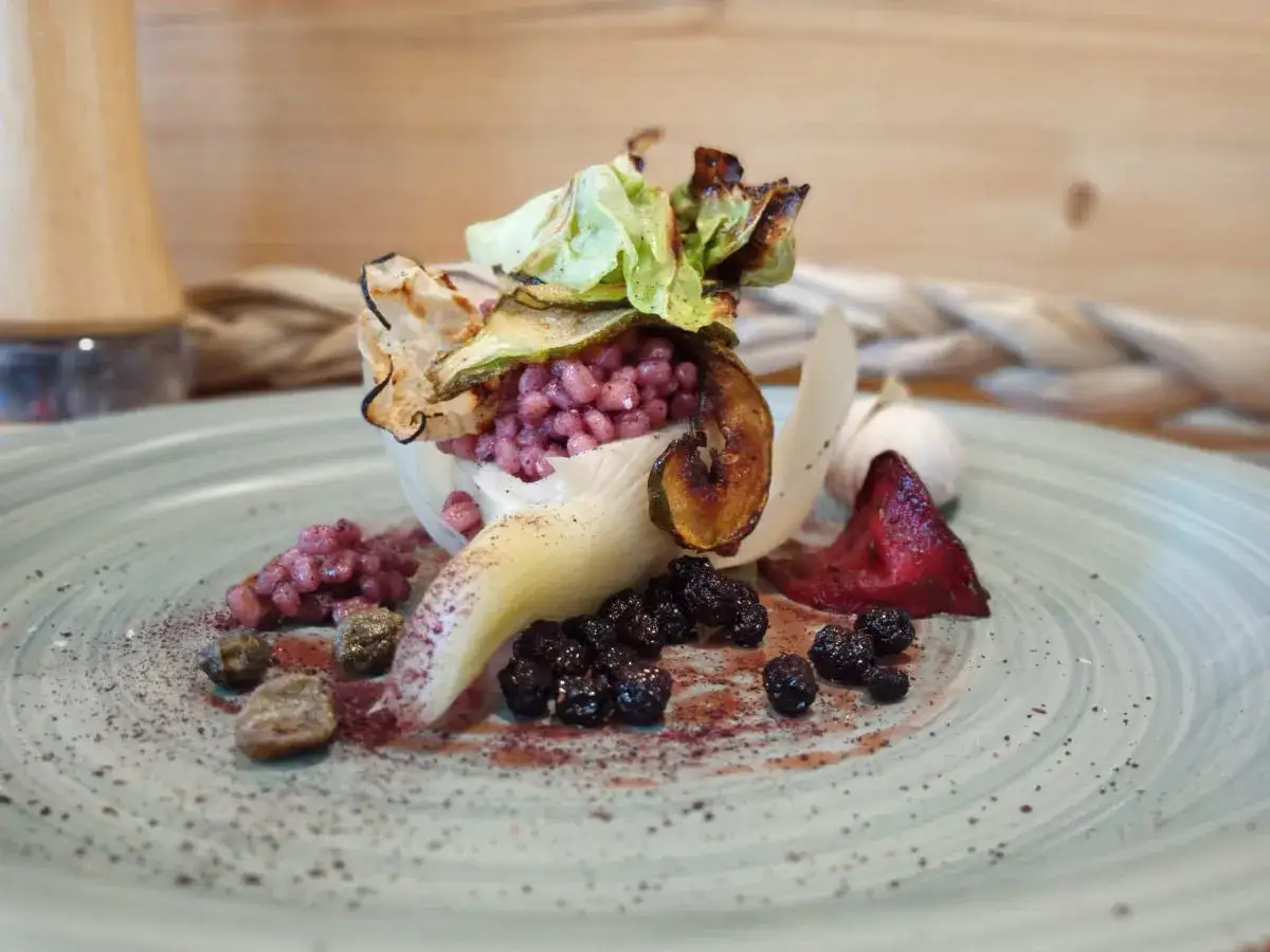 Aronia-Rezept: Rote Beeren, Rote Bete, Zucchini-Chips und Knoblauch auf einem Teller.