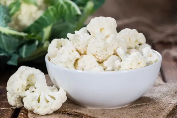 Frischer blumenkohl roh essen ist gesund und lecker. Hier sind Röschen in einer Schüssel und daneben auf einem Holzbrett.