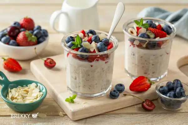 Zwei Gläser mit über Nacht eingeweichten Haferflocken, garniert mit frischen Beeren und Mandelsplittern. Ein gesunder Start in den Tag.