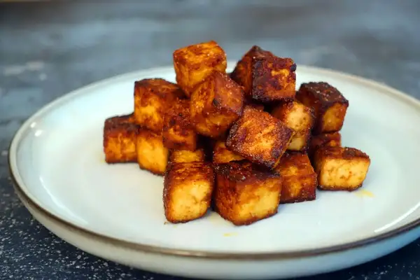 Goldbraun gebratene Tofuwürfel auf einem Teller. Perfekt zum tofu zubereiten für eine knusprige Beilage.