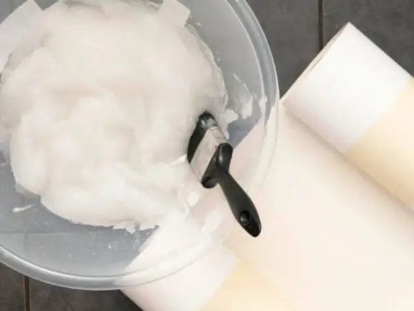Schüssel mit selbstgemachtem Kleister und Pinsel, dane liegen Tapetenrollen bereit.