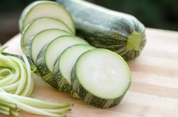 Frische Zucchini, roh essen als Spiralen oder Scheiben auf einem Holzbrett.