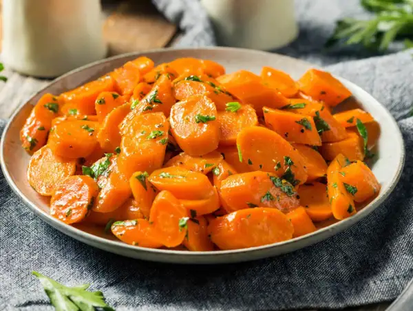 Schüssel mit glasierten, bunte Karotten, garniert mit Petersilie. Ein köstliches Gericht, das Farbe auf den Tisch bringt.
