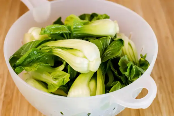 Frischer Pak Choi in einem Sieb, bereit zum rohen Essen. Knackig und grün, eine gesunde Ergänzung für jede Mahlzeit.
